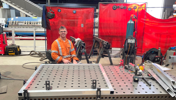 Man in highly visual clothing sitting at his workstation in the boilermaker's shop