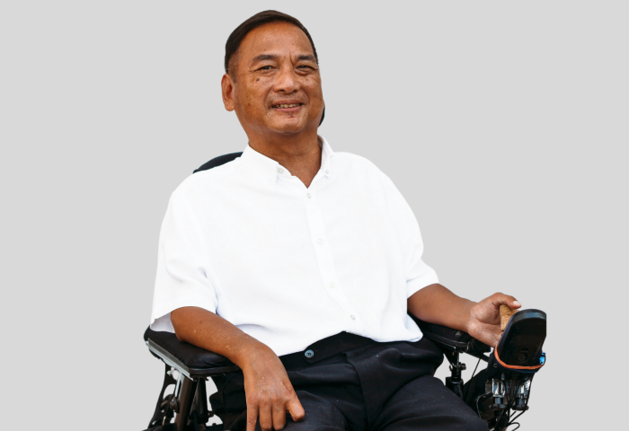  Jude Lee sitting in a wheelchair and smiling at the camera.