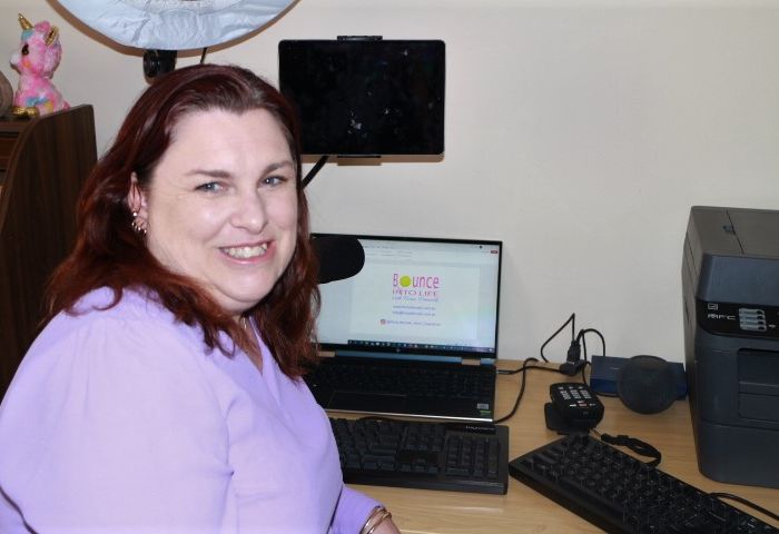 Fiona sitting at her work desk and smiling at the camera