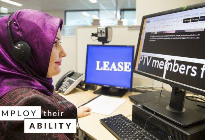 Neslihan Sari, Paralegal at Public Transport Victoria at her desk. Neslihan is looking at her computer and wearing a headset.