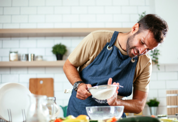 a man using a sieve in a kitchen while cooking