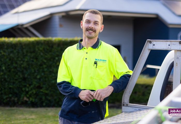 Person with hi-vis top standing against a ute.