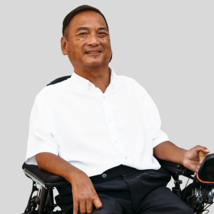  Jude Lee sitting in a wheelchair and smiling at the camera.