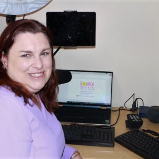 Fiona sitting at her work desk and smiling at the camera