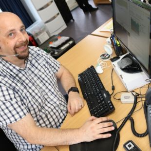 Photo: Daniel Pistritto at his workstation with assistive hearing devices funded by the Employment Assistance Fund (Source: Blamey Saunders hears)