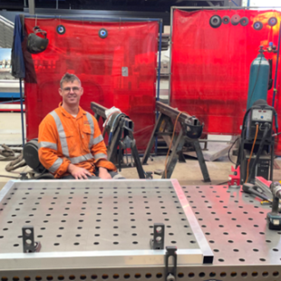 Man in highly visual clothing sitting at his workstation in the boilermaker's shop