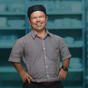 Kevin Green standing in a button-up shirt and a bakers cap