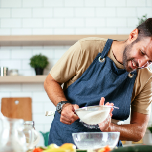 a man using a sieve in a kitchen while cooking