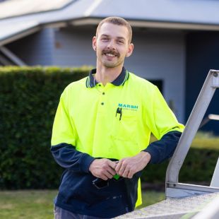 Person with hi-vis top standing against a ute.